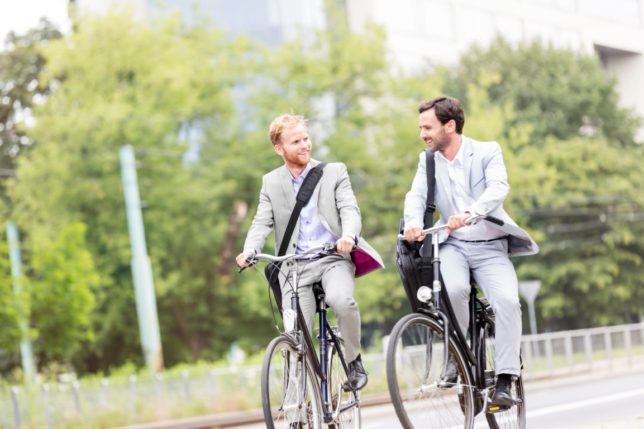 Businessmen talking while cycling outdoors